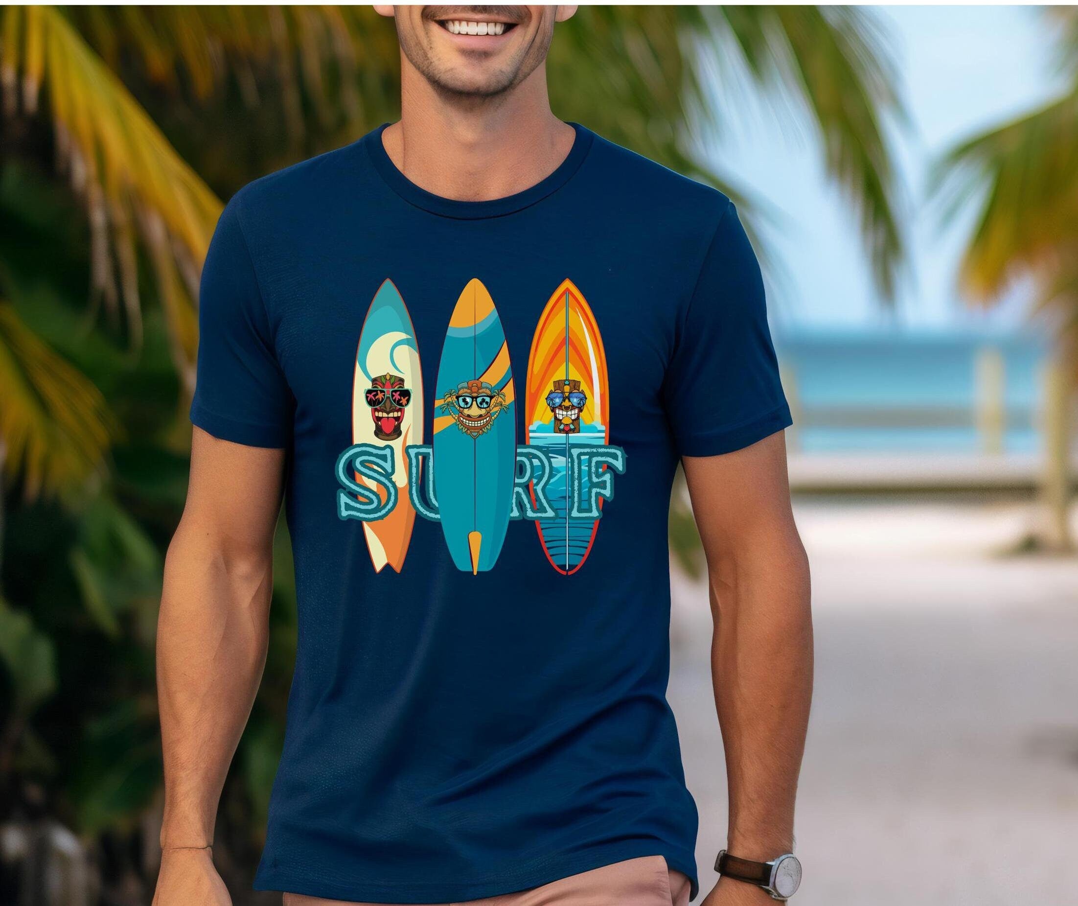 Man wearing a navy blue t-shirt with surfboard design and 'SURF' text, standing on a beach.