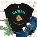 Black t-shirt with 'HAWAII' and a graphic, paired with jeans and sneakers on a wooden surface.