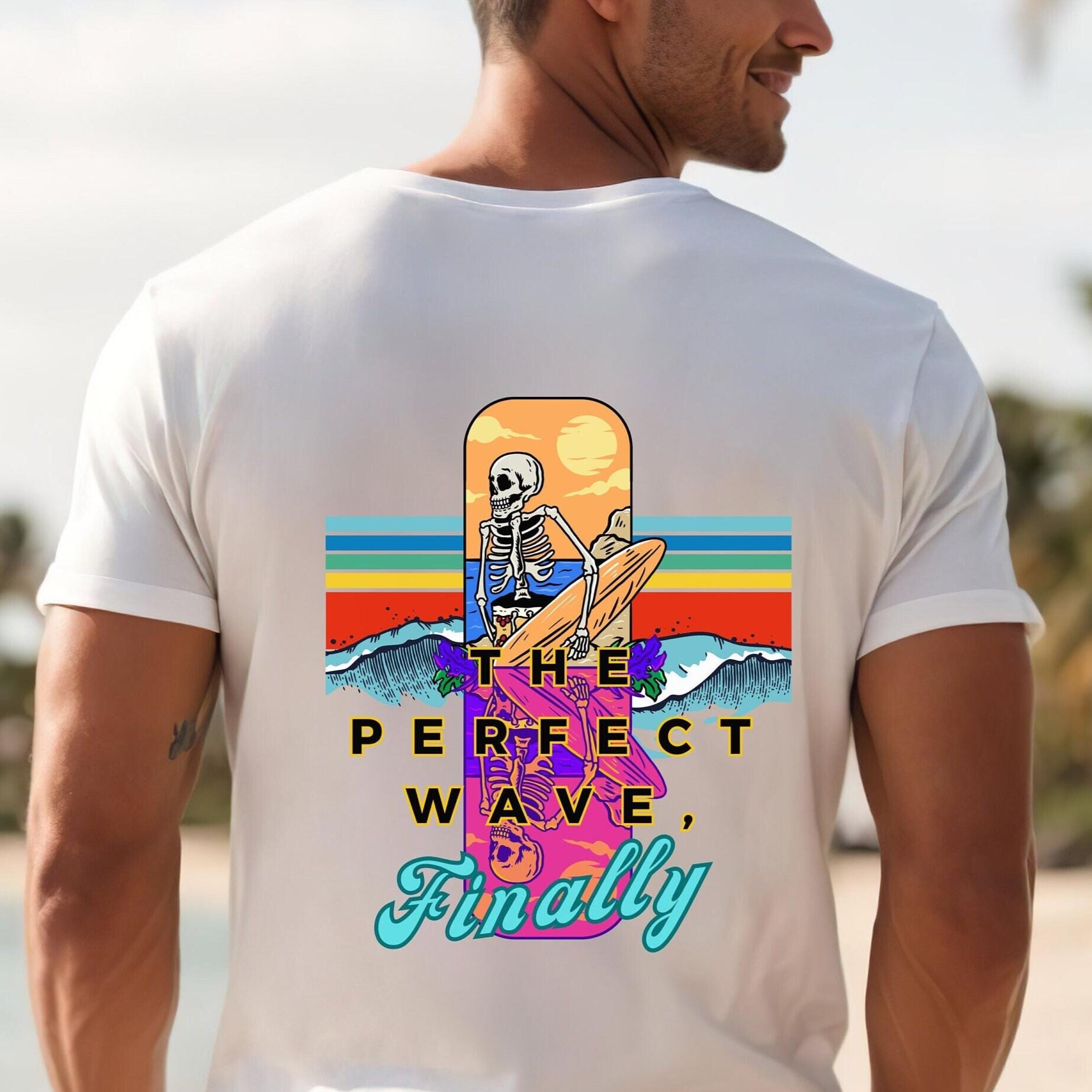 Person wearing a white t-shirt with a colorful graphic design on the back, featuring text and a skeleton surfing.