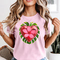 Woman wearing a pink t-shirt with a heart-shaped floral design.