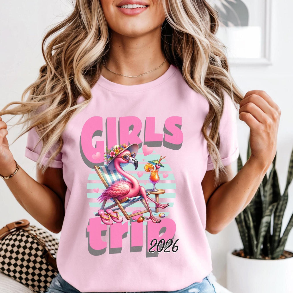 Woman wearing a pink t-shirt with a flamingo graphic and 'Girls Trip 2026' text.