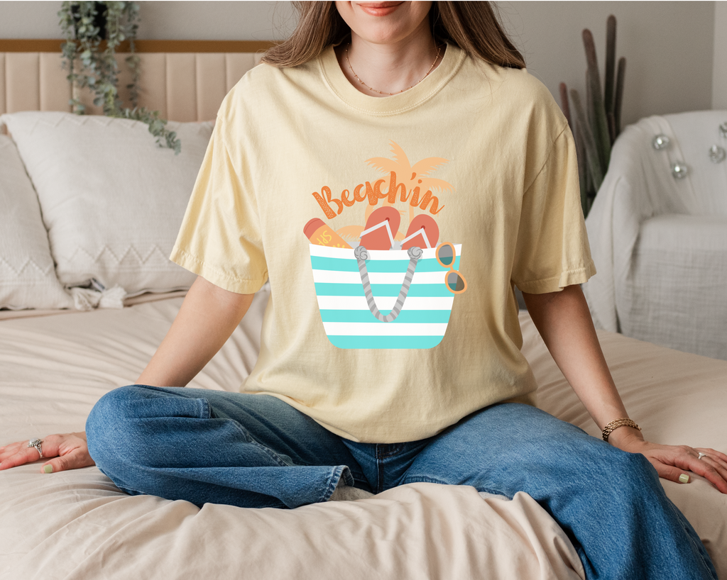 Beachin' summer tee, our best heavyweight cotton shirt,  for over sized choose a size up.  Design features a beach tote with flop flops and sun glasses